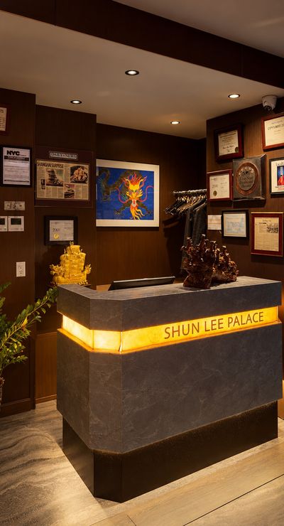 The host stand seen from the side, its gold-lit band glowing beneath framed press clippings and a dragon painting.