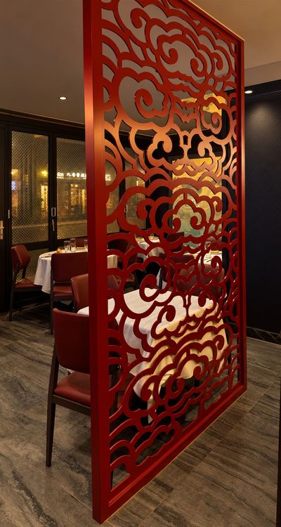 A red carved cloud-pattern screen between tables in the dining room.