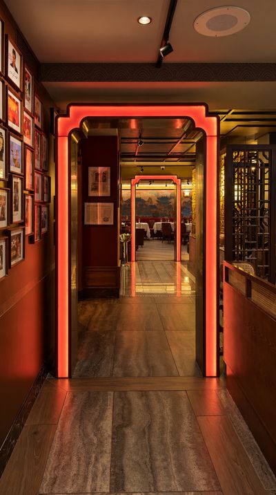 A hallway of glowing orange archways leading toward the dining room, walls hung with framed photographs.