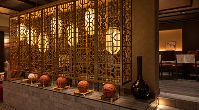 A glowing gold lattice screen with round lantern lights, above a ledge displaying signed basketballs in glass cases.