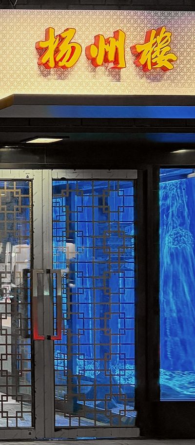 The Shun Lee Palace entrance at night: lattice doors lit in blue beneath the 扬州楼 sign